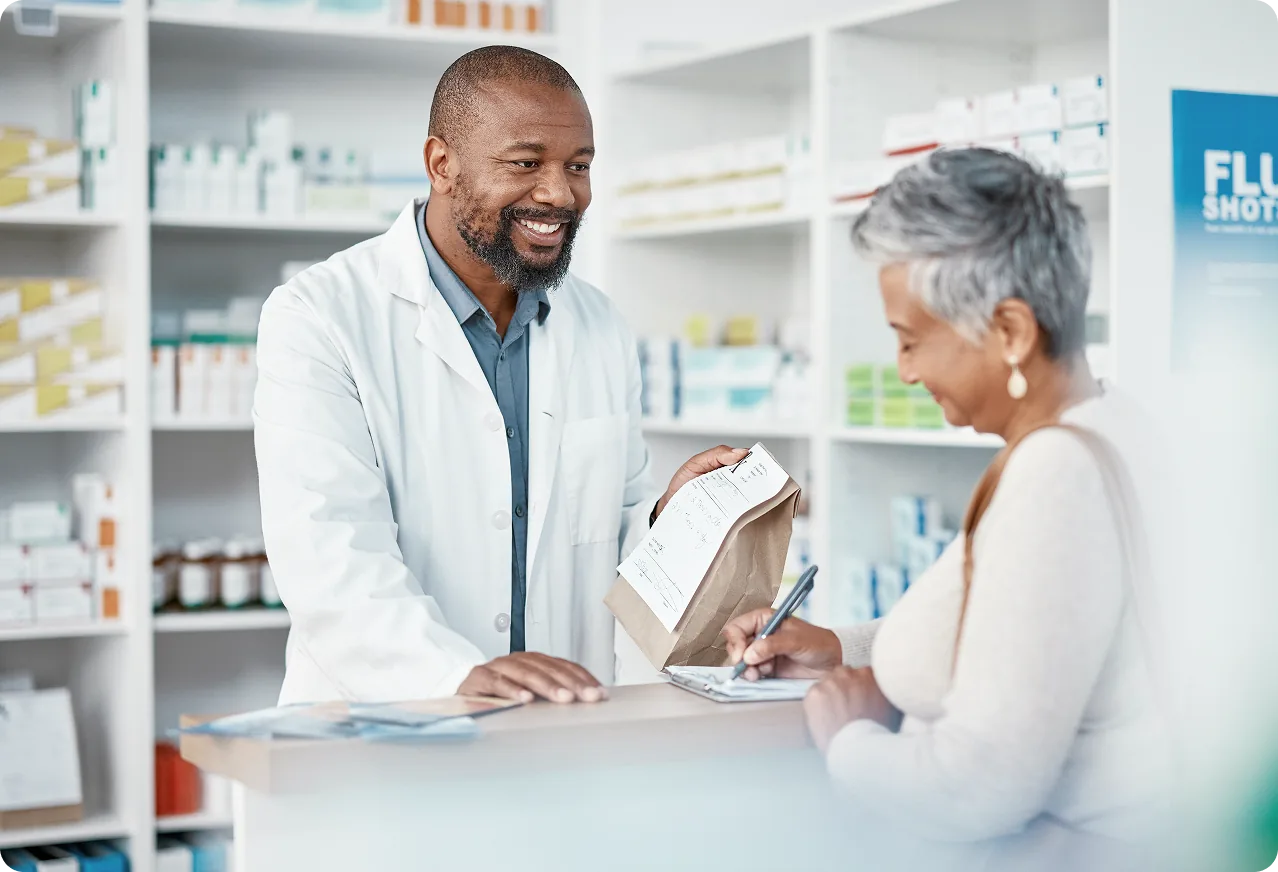Pharmacist helping a patient process enrollment details at a pharmacy counter